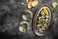 Delicious cooked sea escargo snails with herbs, butter, garlic on metal plate with forks. wine glass. gourmet food. Restaurant Royalty Free Stock Photo