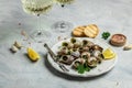 Delicious cooked sea escargo snails with herbs, butter, garlic on metal plate with forks. wine glass. gourmet food. Restaurant Royalty Free Stock Photo