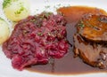 Slices of roast beef with sauce, red cabbage and potato dumplings on a white plate Royalty Free Stock Photo