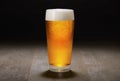 A fresh pint of India Pale ale IPA craft beer served in a cold pint glass at a brewery, black background