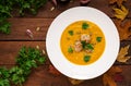 Delicious cream of pumpkin soup with meatballs made of turkey minced meat in a bowl on a wooden table. Royalty Free Stock Photo