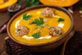 Delicious cream of pumpkin soup with meatballs made of turkey minced meat in a bowl on a wooden table. Royalty Free Stock Photo