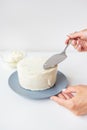 Delicious creamy cake that the girl spreads over the whipped cream with a spatula, the cake is ready for decoration Royalty Free Stock Photo