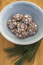 Delicious Crinkles, brown white chocolate flavored cocoa crinkle cookies covered with powdered sugar in blue bowl pine branch