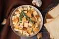 Delicious crispy croutons with rosemary in bowl, toast bread slices and garlic on wooden table, flat lay Royalty Free Stock Photo