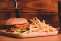 Delicious fish burger with fried potatoes on wooden tray. Royalty Free Stock Photo