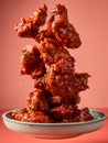 Delicious Crispy Fried Chicken Wings Tossed in Tangy Sauce Levitating Above Bowl on Vibrant Background Royalty Free Stock Photo