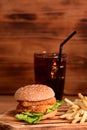 Delicious homemade fish burger and fried potatoes on wooden table. Royalty Free Stock Photo