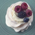Delicious crispy meringue cake with fresh berries. Raspberries and blueberries in the famous dessert of Anna Pavlova.