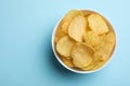 Delicious crispy potato chips in bowl, top view with space for text