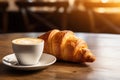 Delicious croissant and cup of coffee on wooden table