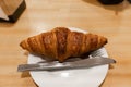 Delicious croissant on a plate with knife and fork, seen from above