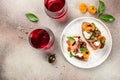 Delicious crostini with prosciutto, cherry tomatoes and cream cheese with basil leaves served with a glass of red wine Royalty Free Stock Photo