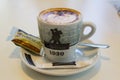 A delicious cup of chocolate sprinkled cappuccino coffee with a biscuit is served in a small restaurant in Playa Las Americas in T