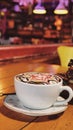 Delicious Cup of hot cappucino is on the wooden table with blur cafe background. Royalty Free Stock Photo