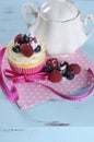 Delicious cupcake with berries and vintage sugar bowl on retro aqua blue shabby chic table