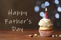 Delicious cupcake with burning candle on table and phrase HAPPY FATHER`S DAY against blurred lights Royalty Free Stock Photo