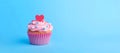 delicious cupcake with cream, decorated with heart and sprinkles, on blue background, copy space,banner, concept of sweet gift for