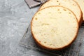 Delicious cut sponge cake on grey textured table Royalty Free Stock Photo