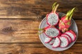 Delicious cut and whole dragon fruits pitahaya on wooden table, top view. Space for text