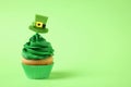 Delicious decorated cupcake on green background, space for text. St. Patrick`s Day celebration