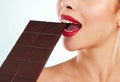 Delicious delicacies. Studio shot of an unrecognizable young woman biting into a slab of chocolate against a light