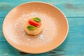 Delicious dessert. Beige dish with cheesecake with strawberries and mint on a turquoise wooden table
