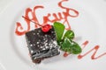 Delicious dessert. A piece of chocolate cake with powder, cherry and mint. Horizontal frame Royalty Free Stock Photo