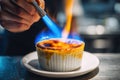 Delicious dessert preparation with a chef using a torch to caramelize sugar on a custard dish in a kitchen setting Royalty Free Stock Photo