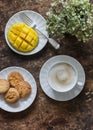 Delicious dessert, snack on a wooden table - cappuccino, fresh ripe mango, cookies, top view