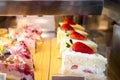 Delicious desserts with strawberries sponge cakes on display in cafe, sweet bakery window display cake with pastries in the store Royalty Free Stock Photo