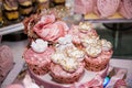 Delicious desserts at the wedding candy bar in the buffet area: muffins decorated with angels, sugar rosebuds and gold dye