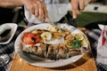 Delicious Dinner at the restaurant. Mediterranean food. Grilled fish and vegetables on a plate. Hands of person cutting fish in a Royalty Free Stock Photo