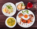 Delicious dinner table with grilled meat and vegetables, fresh vegetables salad, chicken soup, toast with cheese and compote Royalty Free Stock Photo