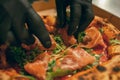 Delicious dish. Chef puts slices of prosciutto on hot baked pizza in cardboard box. Looks tasty, aromatic Royalty Free Stock Photo
