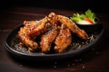 A delicious dish consisting of chicken wings served on a black plate alongside a side of fresh salad, Delicious crispy BBQ chicken Royalty Free Stock Photo