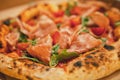 Delicious dish. Hot baked pizza with meat, prosciutto and greens in cardboard box. Looks tasty, aromatic Royalty Free Stock Photo