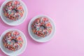 Delicious donuts with multi-colored sprinkles on a pink background