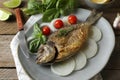 Delicious dorado fish with vegetables and herbs served on wooden table