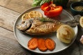 Delicious dorado fish with vegetables served on wooden table