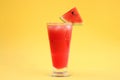 Delicious drink with piece of watermelon and ice cubes on yellow background Royalty Free Stock Photo
