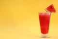 Delicious drink with piece of watermelon and ice cubes on yellow background, space for text Royalty Free Stock Photo