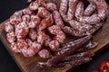 Delicious dry sausage with walnuts on a concrete table. Dry cured fuet sausage on a dark background Royalty Free Stock Photo