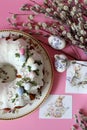 A delicious Easter cake - a ring in white icing on a pink table background next to willow branches and Easter eggs. Royalty Free Stock Photo