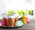 Delicious Easter cakes, painted eggs and tulips on wooden table indoors