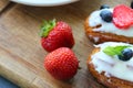 Delicious eclairs with strawberries and blueberries on a wooden cutting Board.