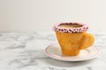 Delicious edible biscuit cup of coffee decorated with sprinkles on white marble table, space for text