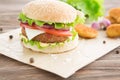 Delicious fast food. Cheese burger with grilled meat, cheese, tomato, on craft paper on wooden surface. Fast food Royalty Free Stock Photo