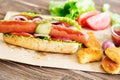 Delicious fast food. Hot dog with sausage, cucumber, tomato and lettuce on dark wooden background. Summer hotdog. Royalty Free Stock Photo