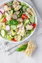 Delicious Fattoush or Arab salad with pita bread, fresh vegetables and basil on white plate. Middle Eastern bread salad. Top view